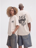 Two people wearing matching white t-shirts with graphic designs on a plain background